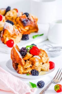 Crock pot french toast casserole topped with berries and mint, on a white plate.