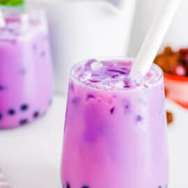 Taro milk tea in a glass with a straw.