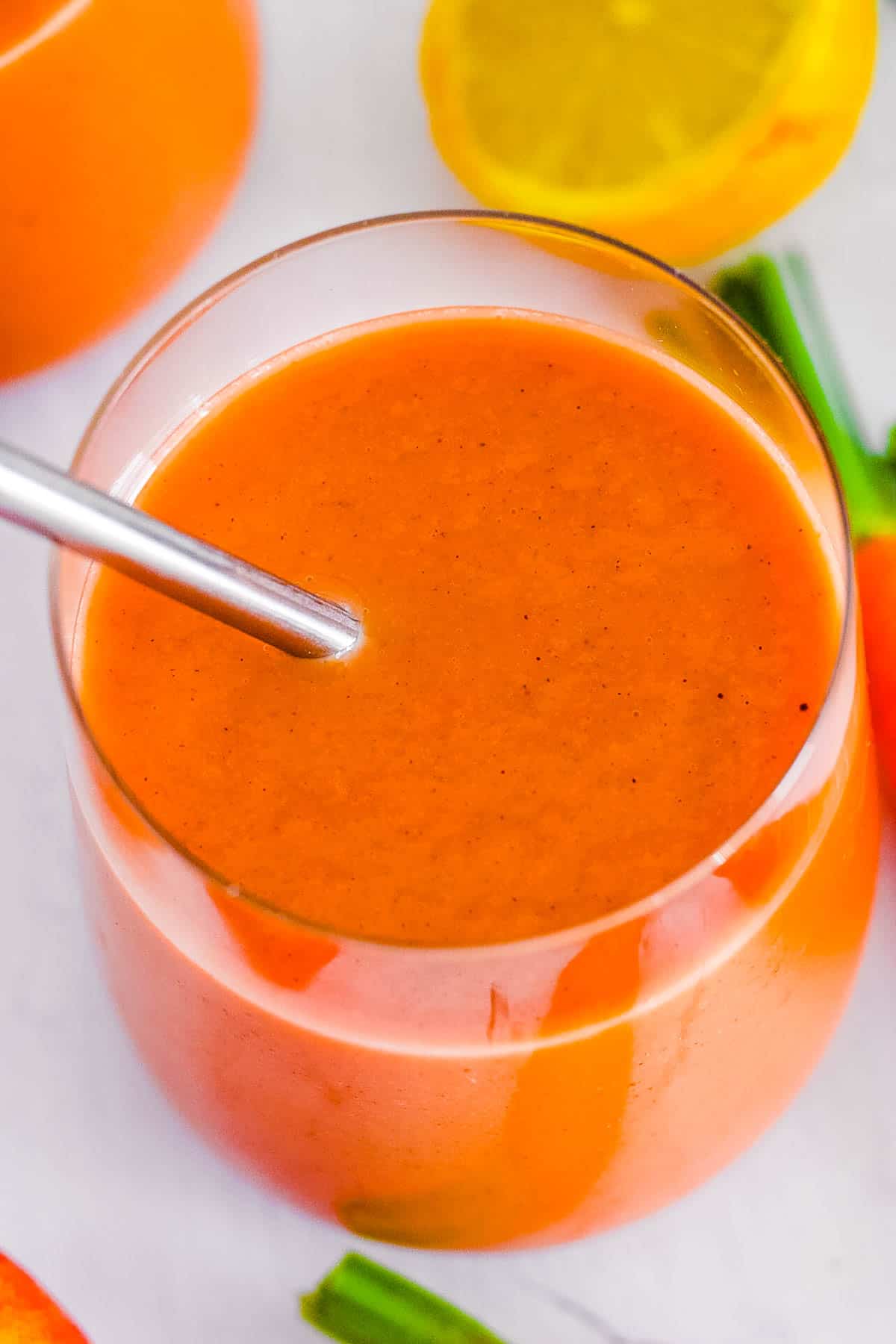 Vegan apple carrot smoothie with banana in a glass with a straw.