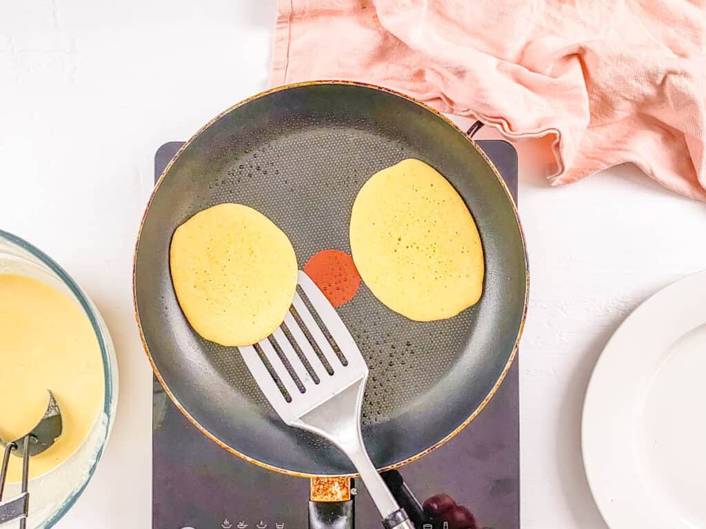 Vegan coconut flour pancakes cooking in a pan.