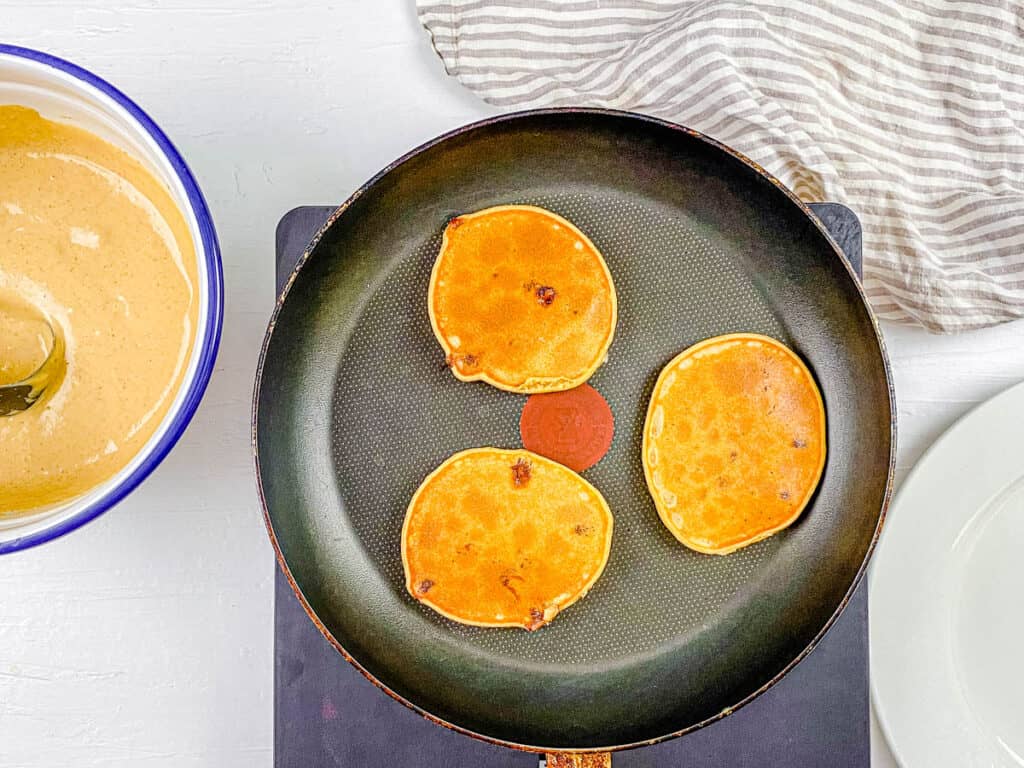 Pancakes cooking in a skillet.