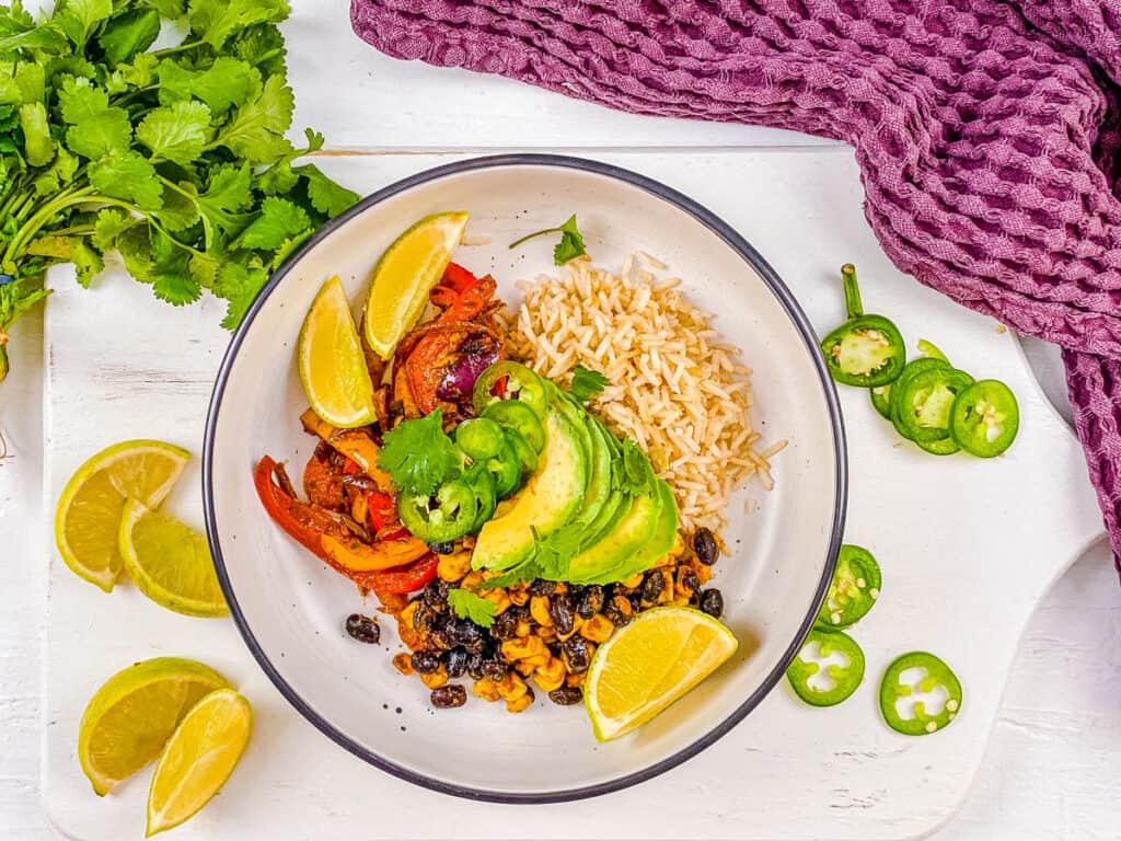 Vegetarian burrito bowl with avocado and lime, on a white background.