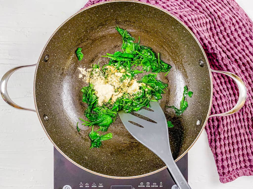 Spinach and spices sauteeing in a pan.