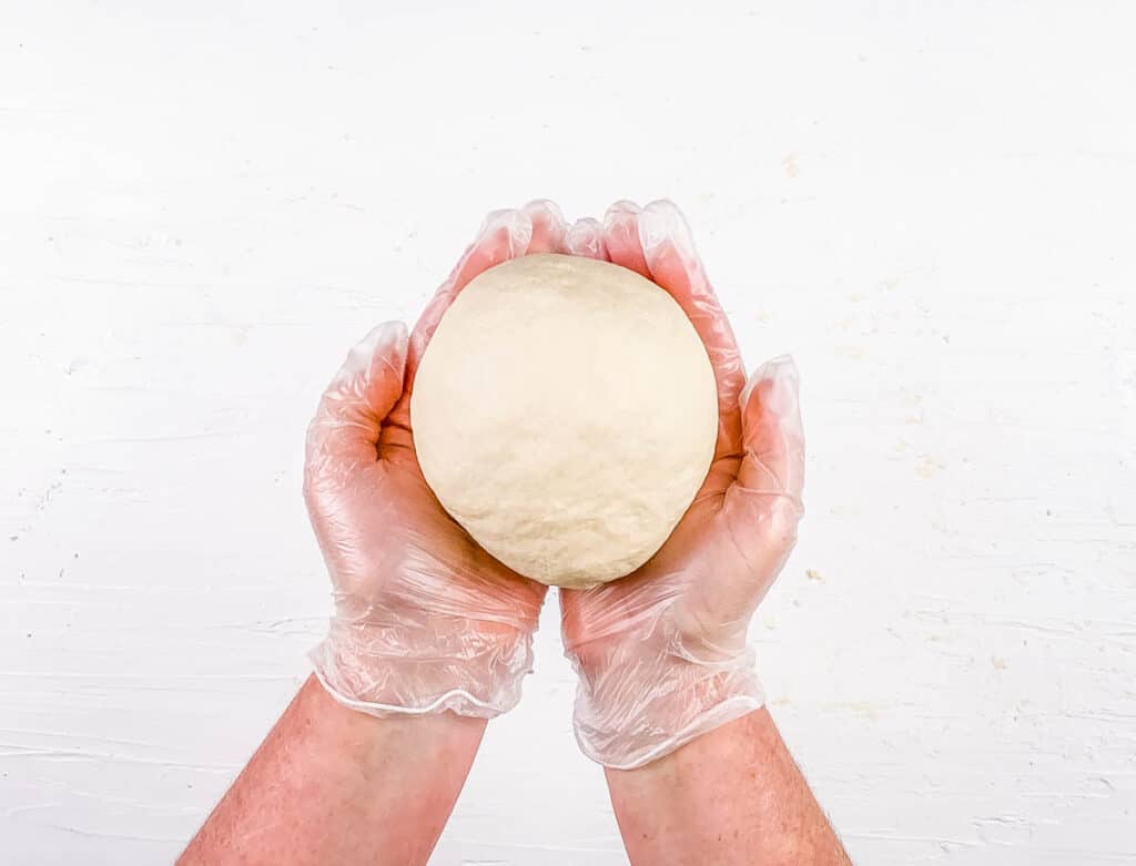 3 ingredient vegan pasta dough being held by two hands.