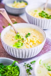 4 ingredient potato soup served in a white bowl, topped with green onions and shredded cheese.