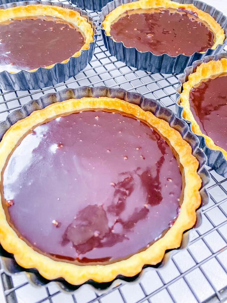 Baked chocolate mini tarts on a wire rack.