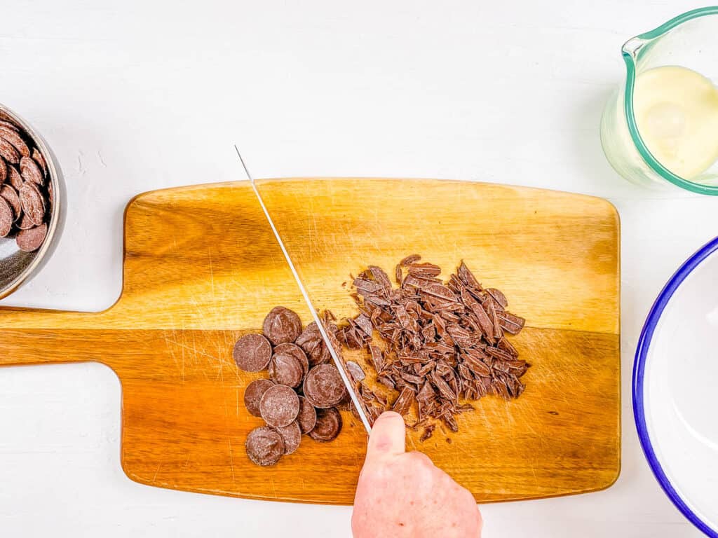 Chocolate bar being chopped on a cutting board.