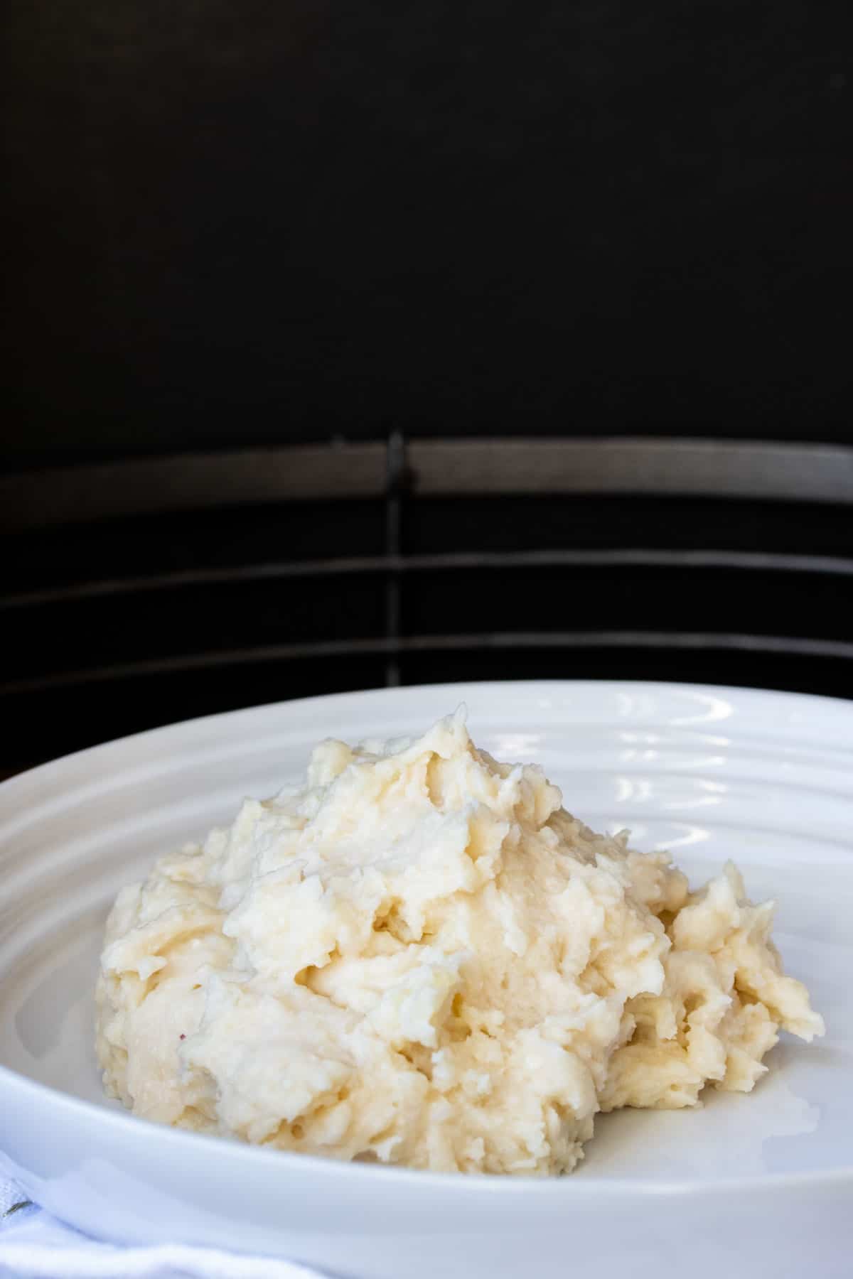 Pile of plain mashed potatoes on a white plate