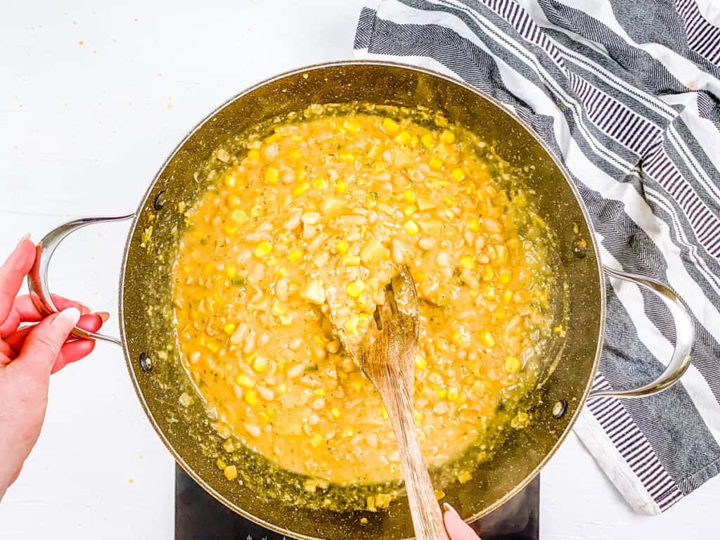 Creamy vegan white bean chili cooking in a stock pot on the stove.