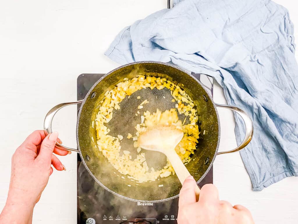 Diced onions sauteeing in a stock pot.