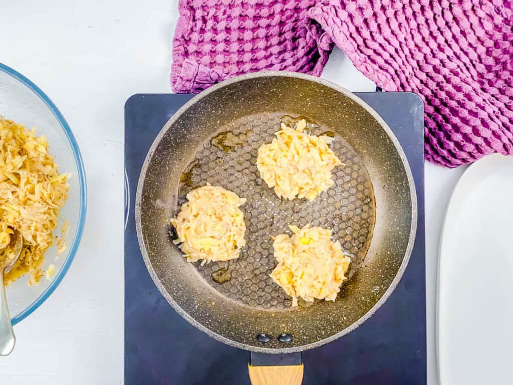 Eggless potato pancakes cooking in a nonstick skillet.