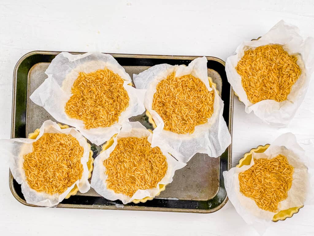 Rice filled into pastry crust shells before baking in the oven.