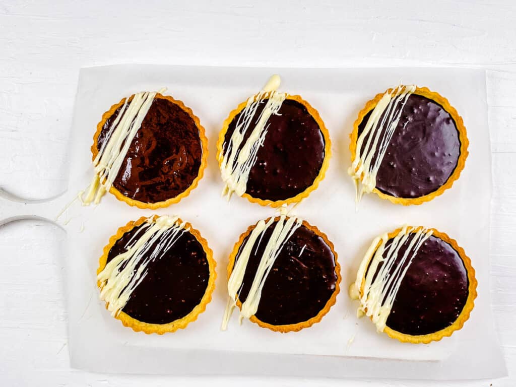Individual mini chocolate tarts on a white tray.