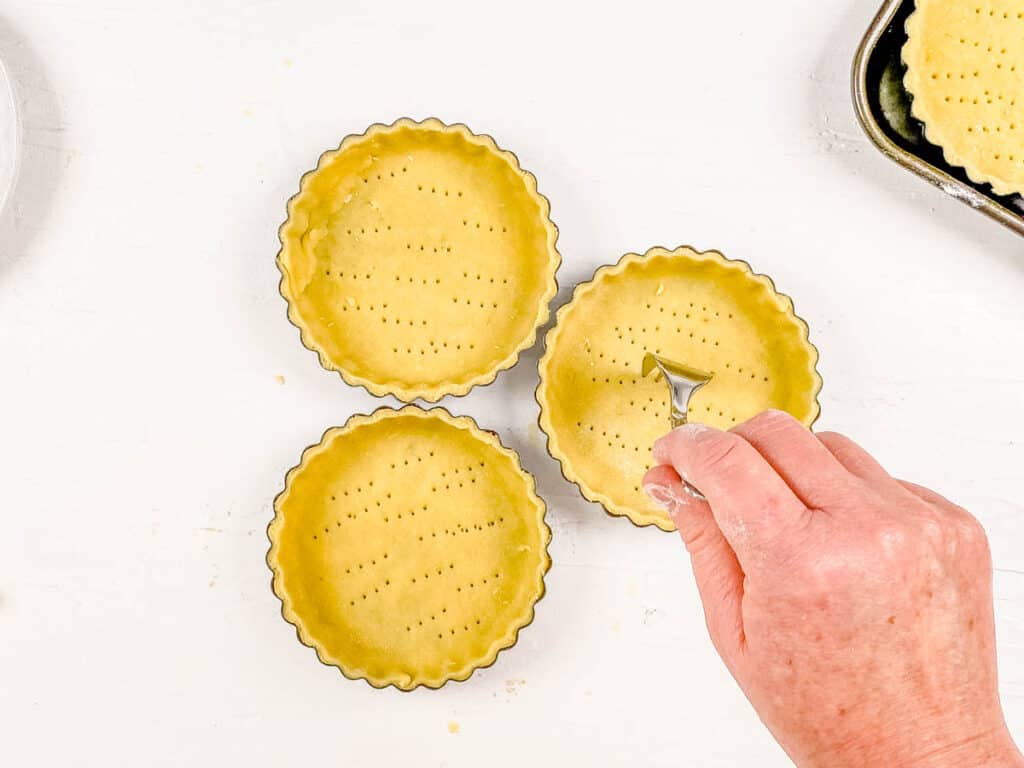 Mini chocolate tart shells being poked with a fork for aeration before baking.