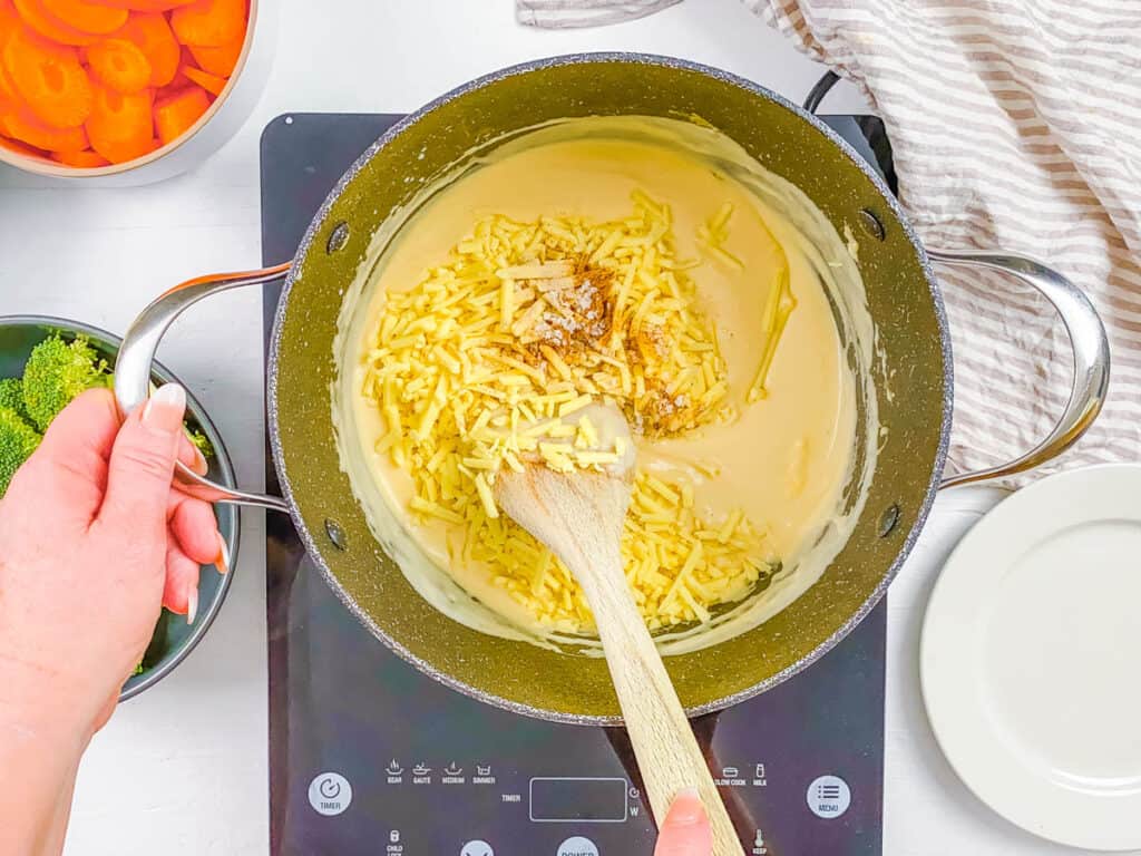 Cheese mixed into bechamel sauce on the stove in a large pot.