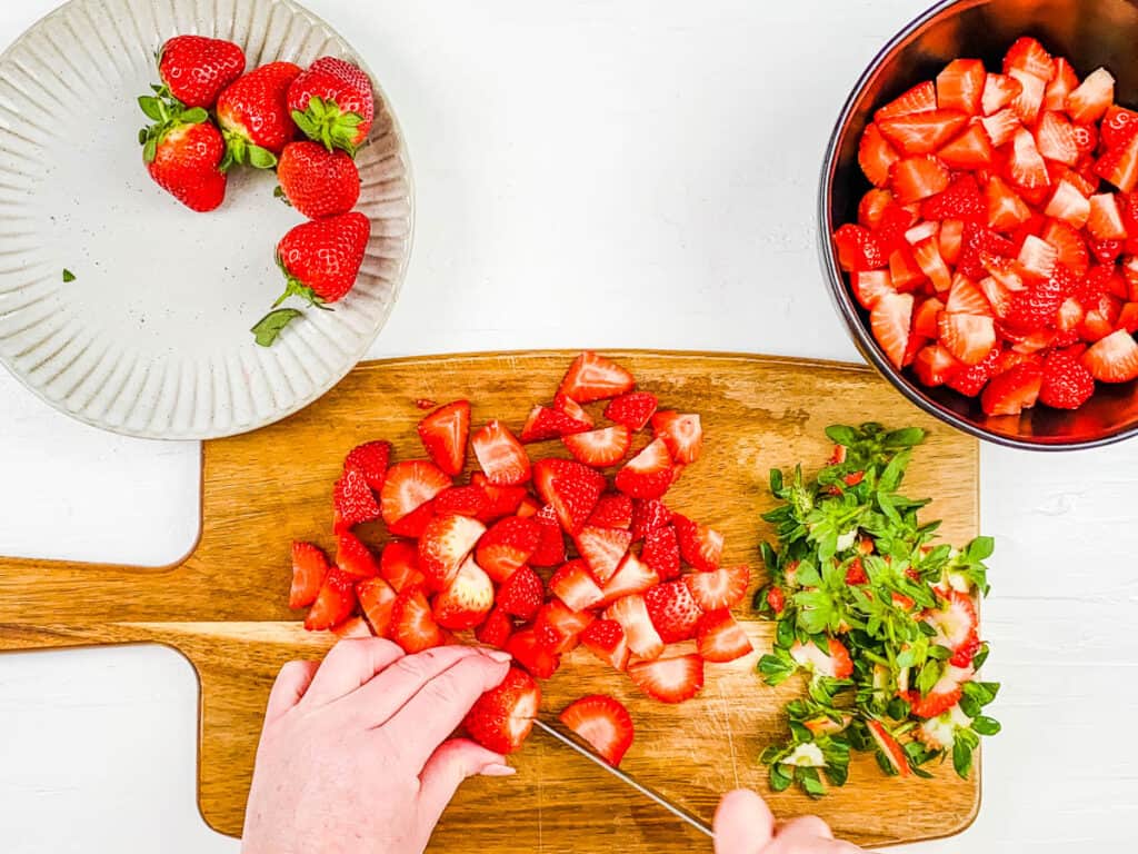 Fresh strawberries cut on a cutting board.