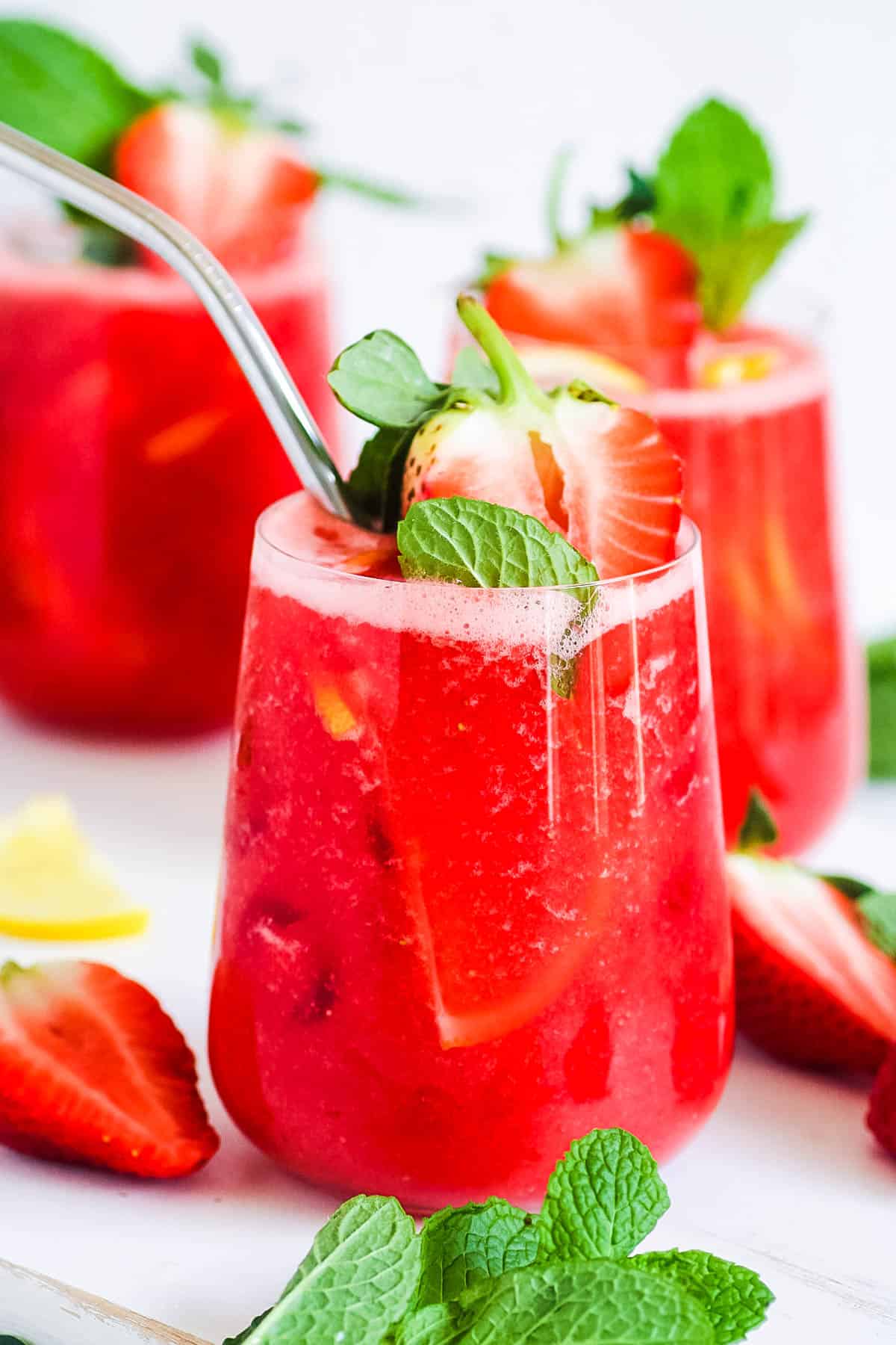 Strawberry juice in a gl، with a straw, garnished with fresh strawberries and mint.