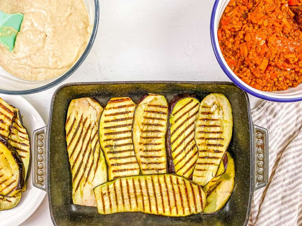 Grilled eggplant layered in a baking dish.