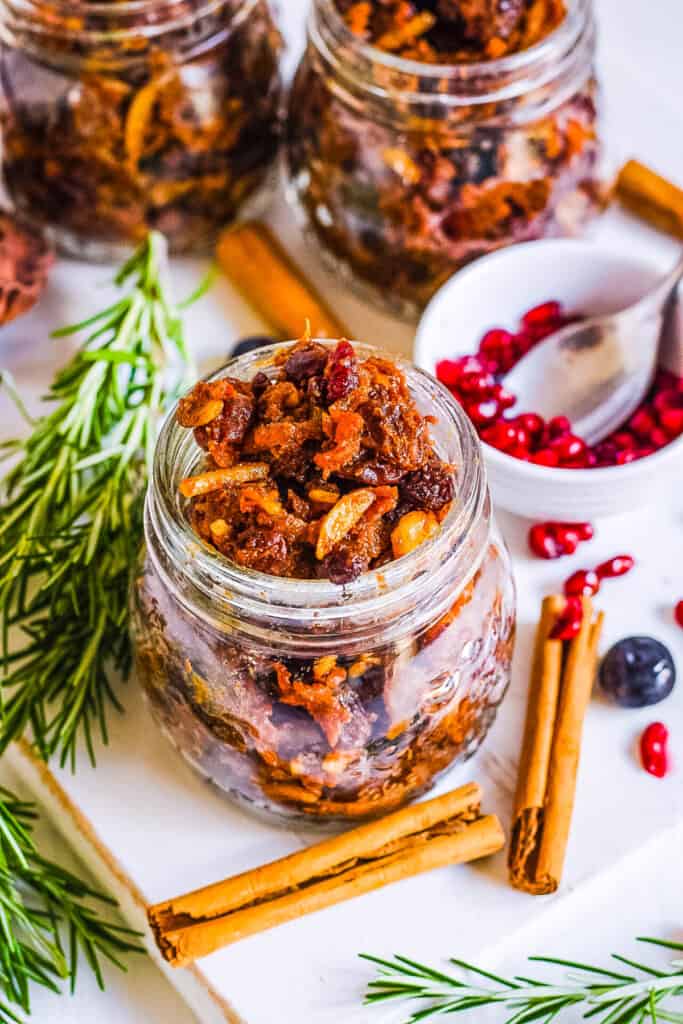 Vegan mincemeat in glass jars with holiday decorations surrounding the jars.
