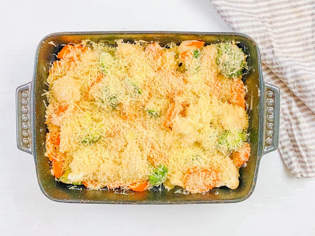 Carrots broccoli and cauliflower gratin in a casserole dish topped with cheese.