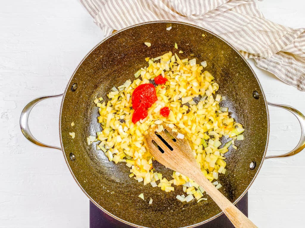 Onions and tomato paste sauteeing in a pan.