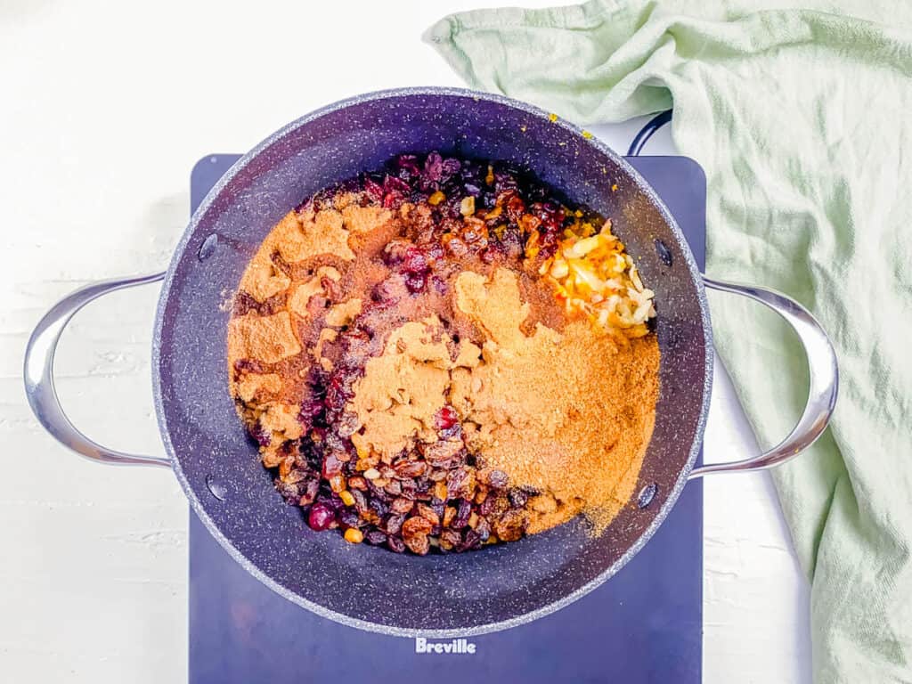 Dried fruit and spices cooking in a stock pot on the stove.