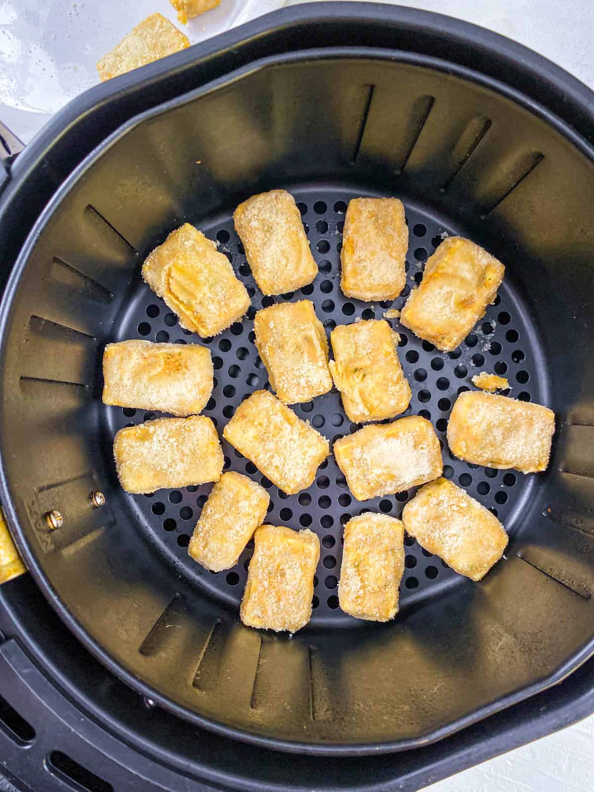 Air fryer tofu nuggets in the basket of an air fryer.