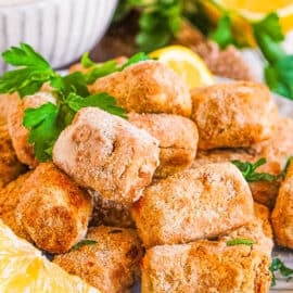 Air fryer tofu nuggets on a plate with lemon and parsley as a garnish.