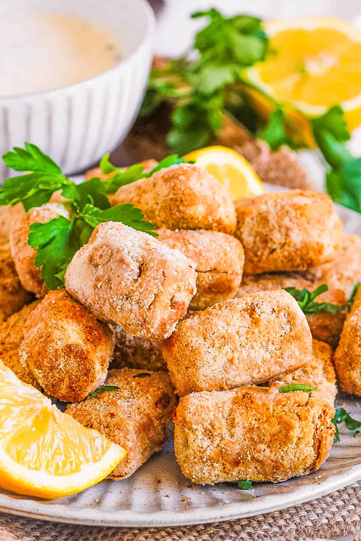 Air fryer tofu nuggets on a plate with lemon and parsley as a garnish.