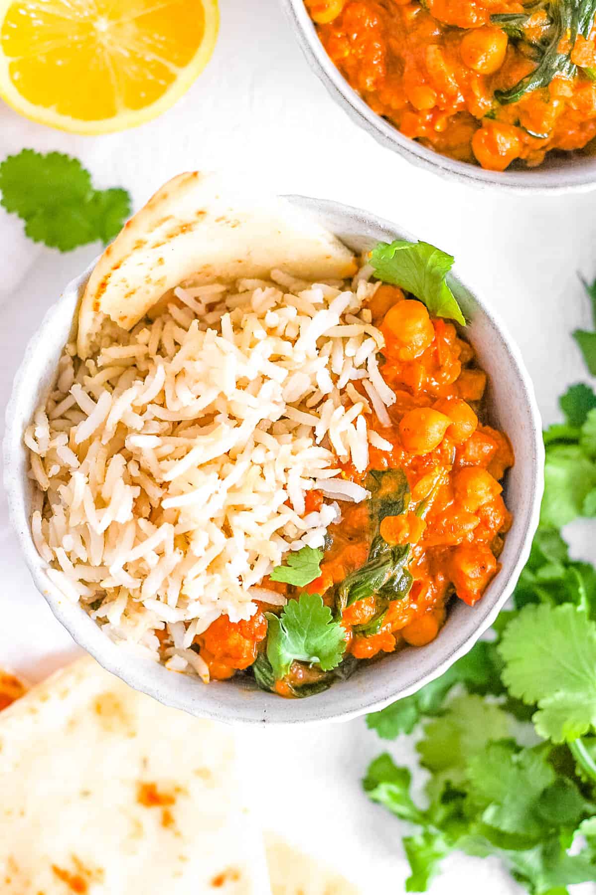 Chickpea and lentil curry served with rice and naan in a white bowl.