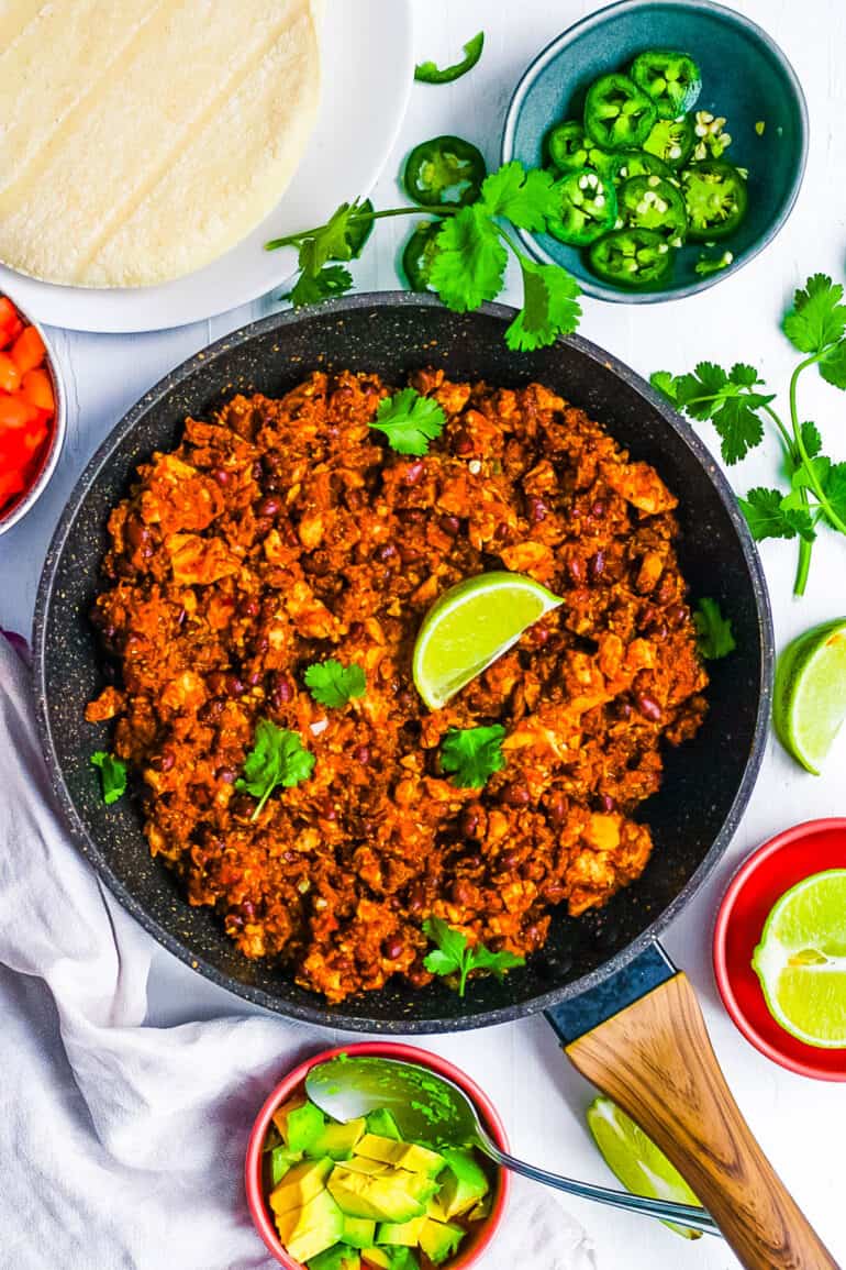 Chipotle copycat sofritas in a cast iron skillet topped with cilantro and lime wedges.