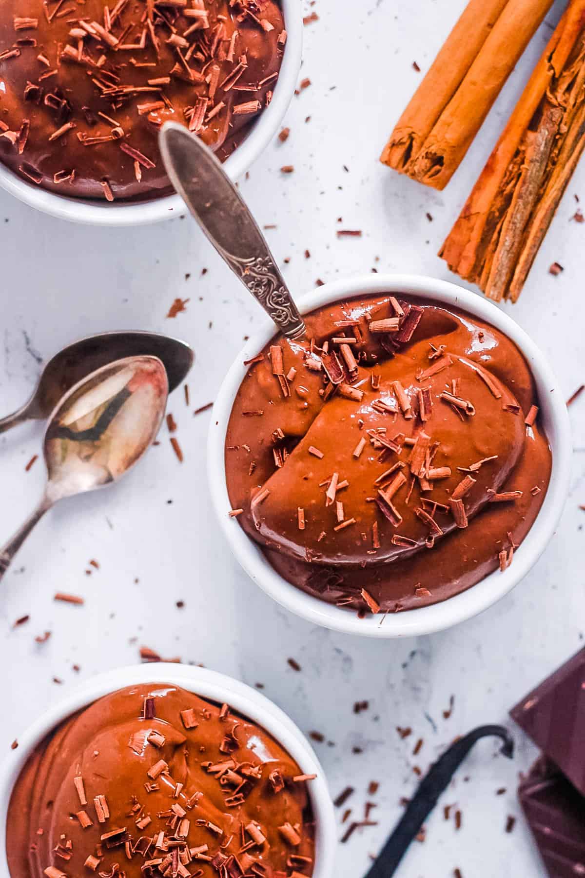 Healthy chocolate almond milk pudding served in white bowls topped with chocolate shavings.