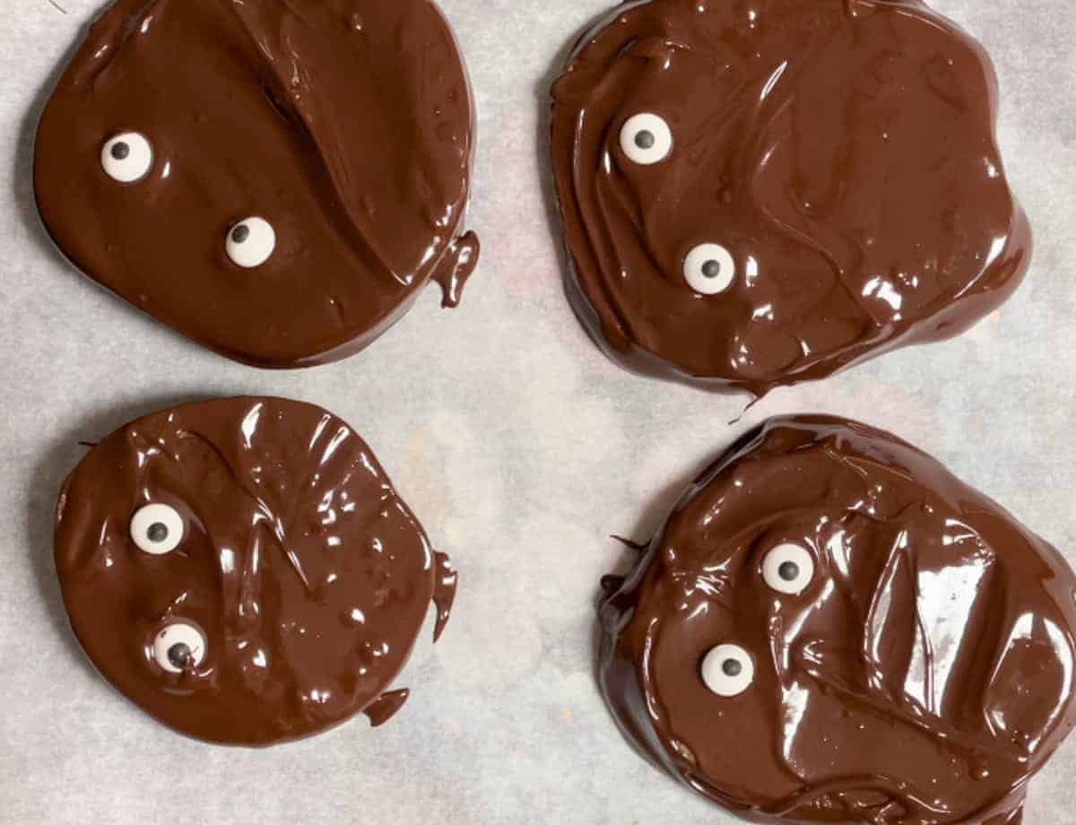 Adding candy eyes to chocolate apple slices.