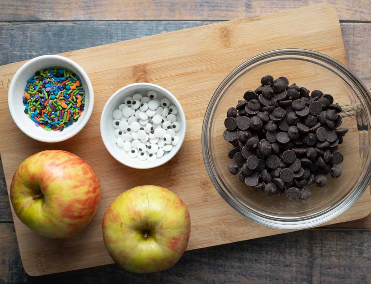 Two apples, chocolate chips, candy eyes, Halloween sprinkles.