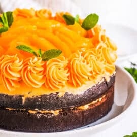 Chocolate mango cake on a white cake platter.