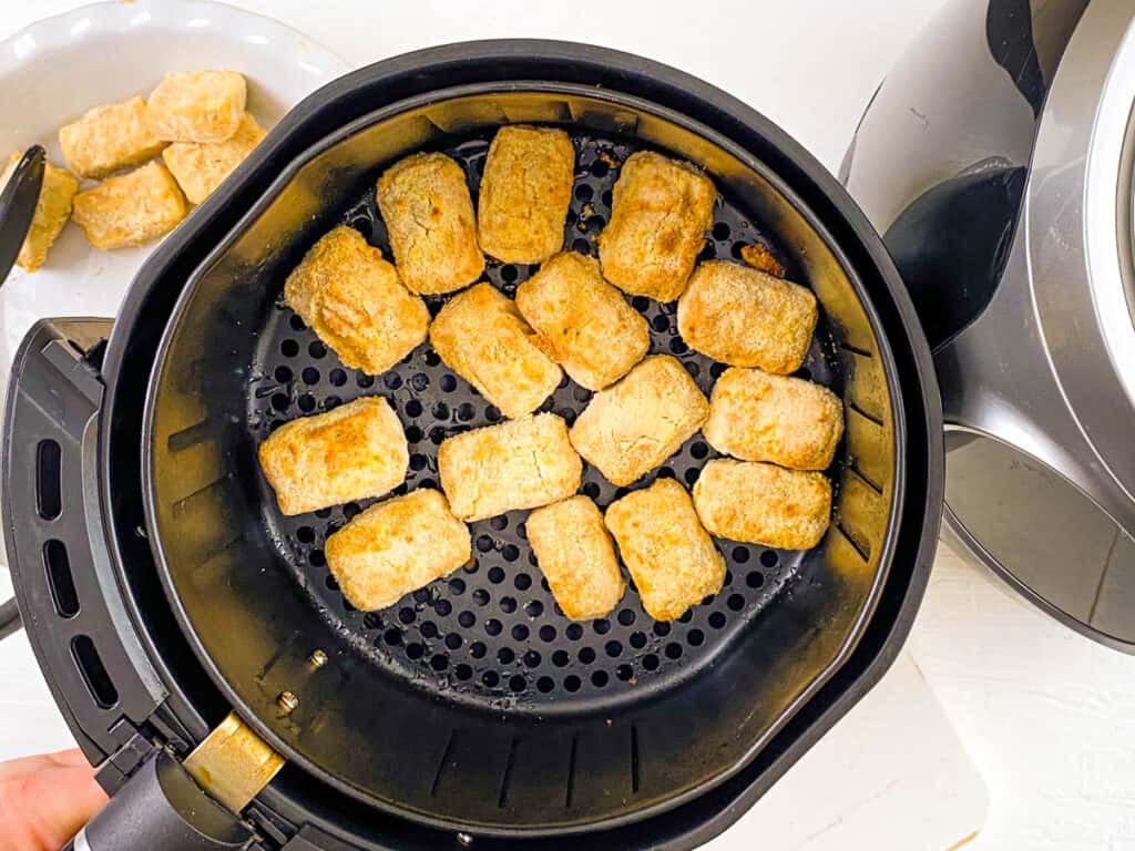 Crispy air fried tofu puffs in the basket of an air fryer.