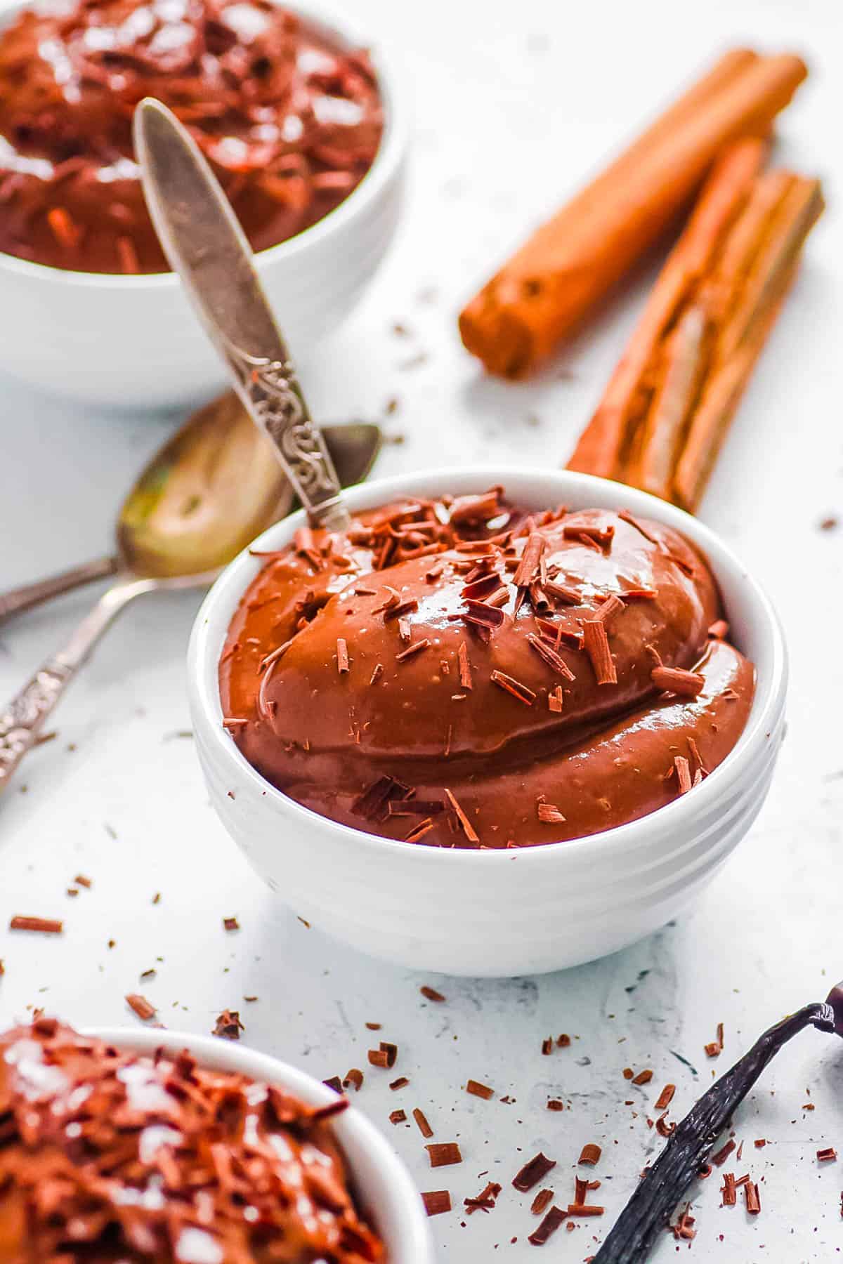 Healthy chocolate almond milk pudding served in white bowls topped with chocolate shavings.