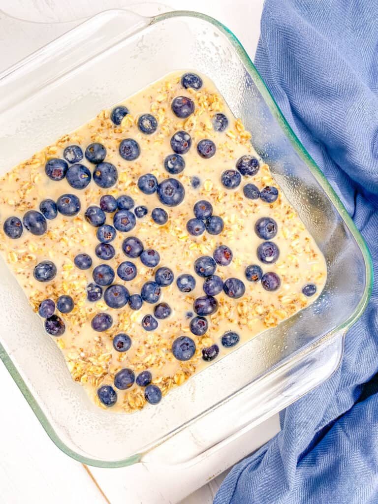 Eggless baked oats with blueberries in a baking dish, ready to be placed into the oven.