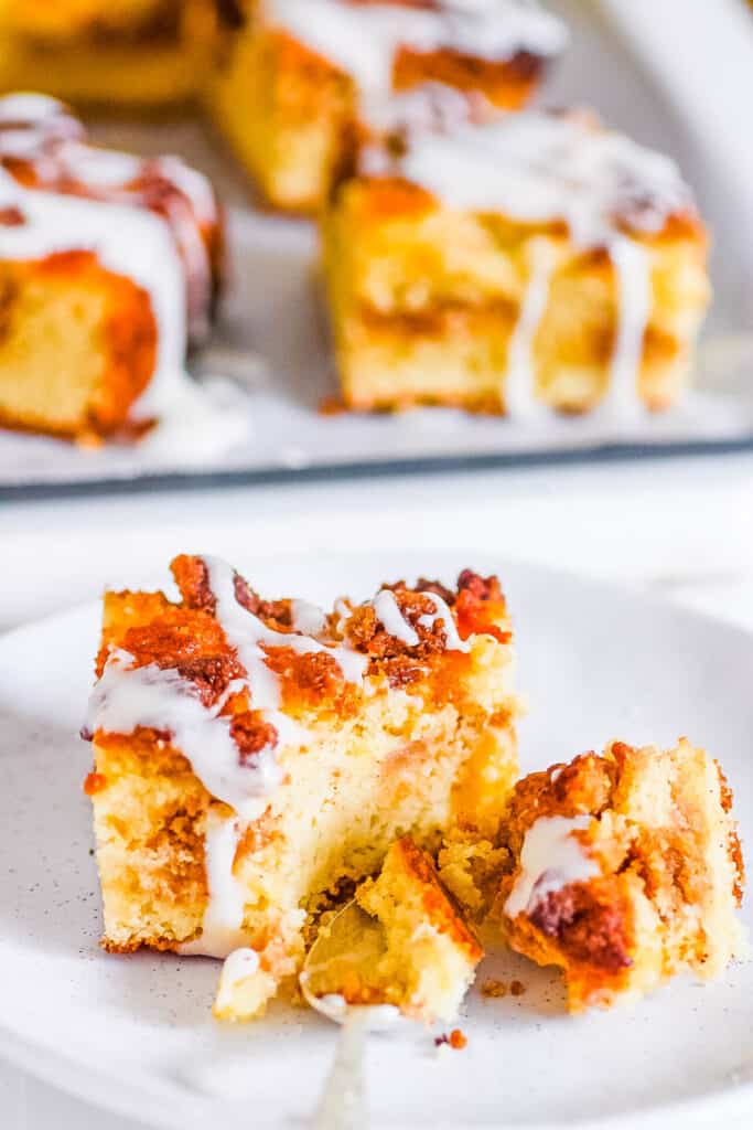 Slice of keto coffee cake with a vanilla glaze on a white plate.