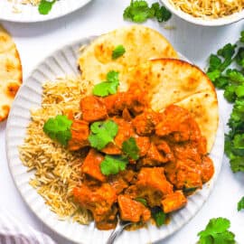 Vegan tikka masala served with rice and naan on a white plate.