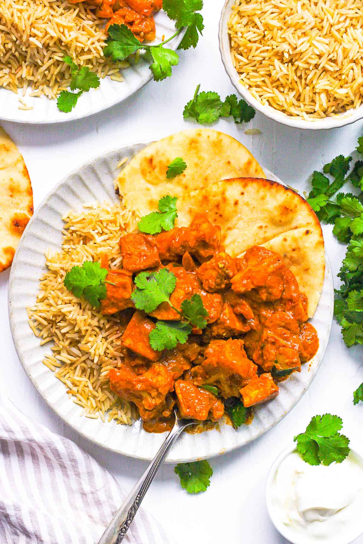 Vegan tikka masala served with rice and naan on a white plate.