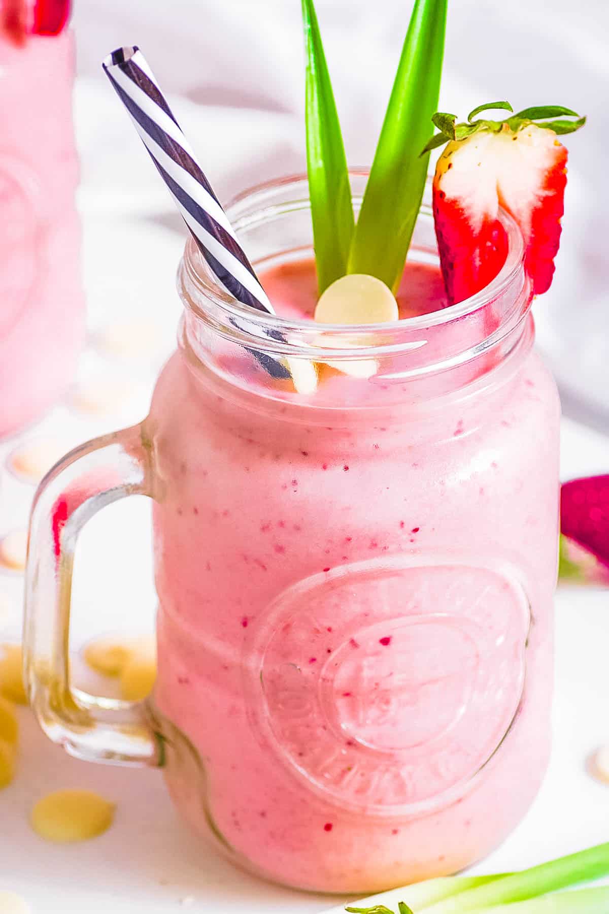 Bahama mama tropical smoothie recipe copycat in a gl، mug garnished with white c،colate and strawberries.