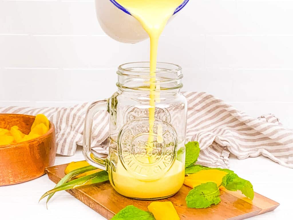 Jackfruit pineapple smoothie being poured into a mason jar.
