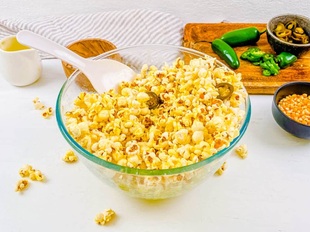 Popcorn with jalapenos in a mixing bowl.
