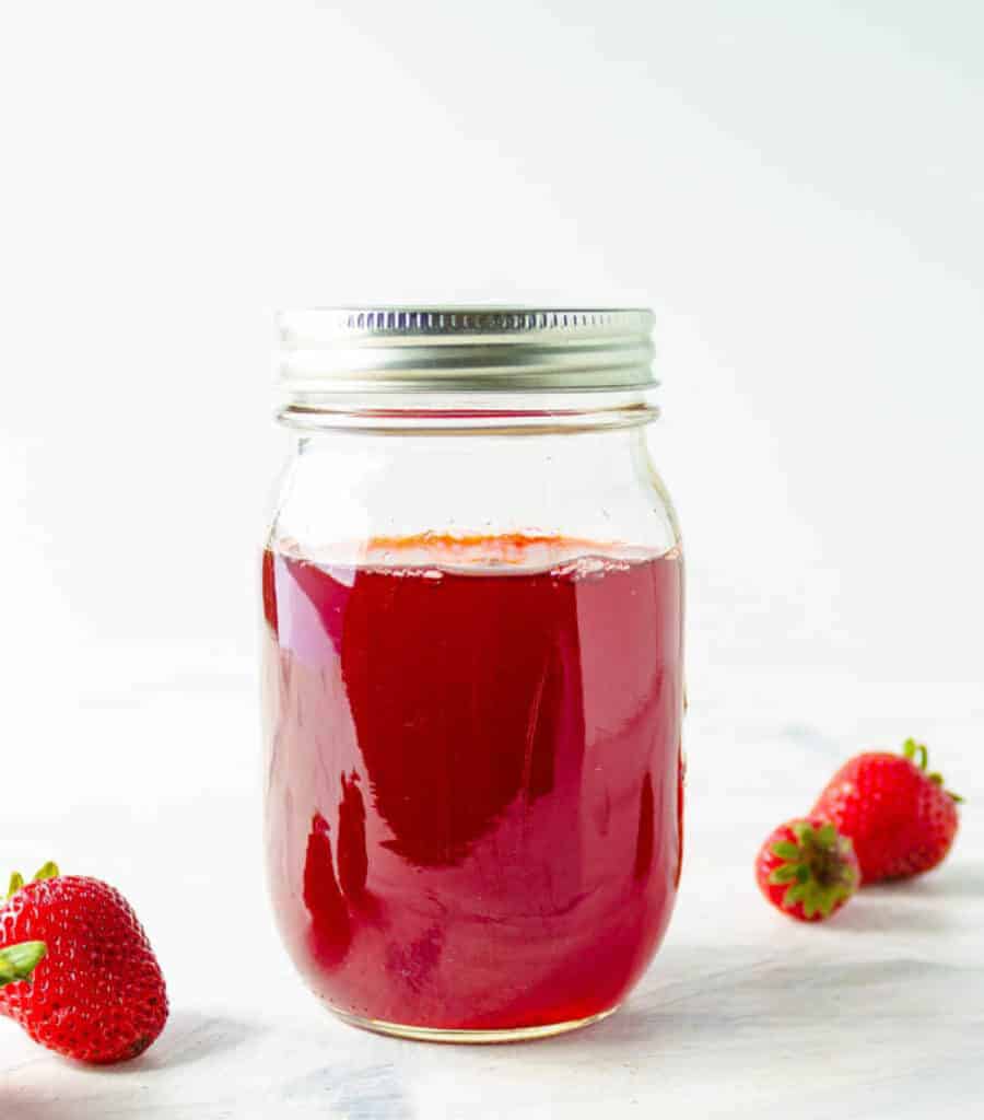 Homemade easy strawberry simple syrup stored in a mason jar.