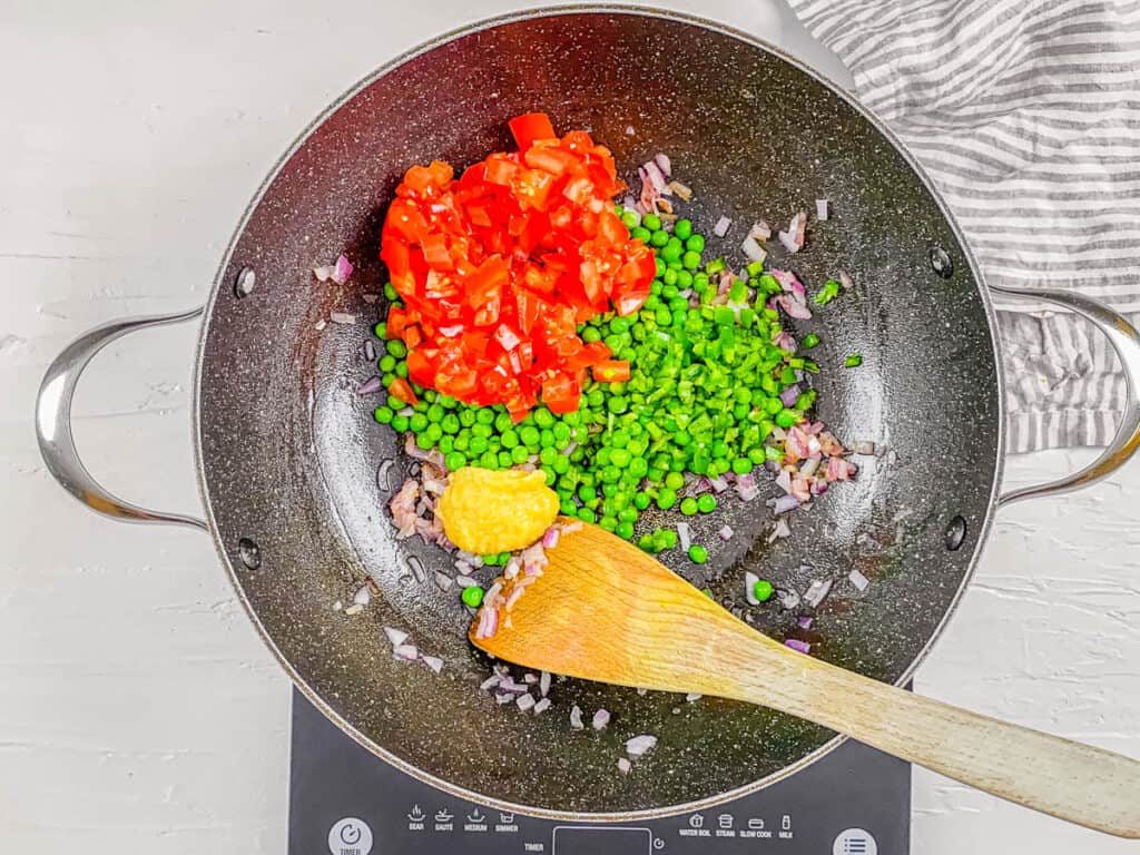 Peas, tomatoes, onions and spices cooking in a pan.