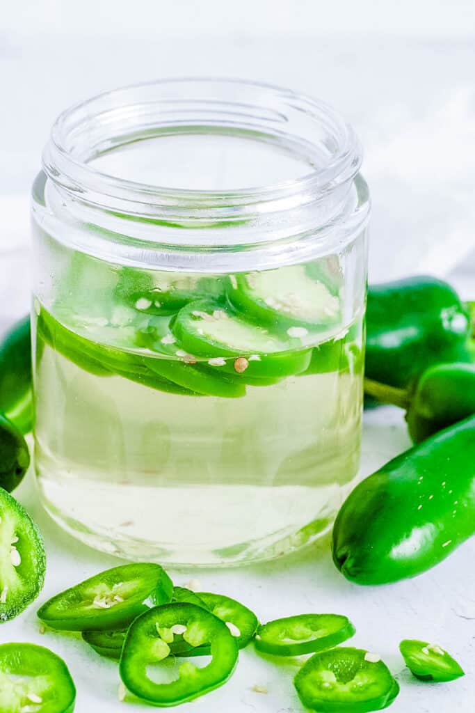 Jalapeno simple syrup in a glass mason jar, garnished with jalapeno slices.