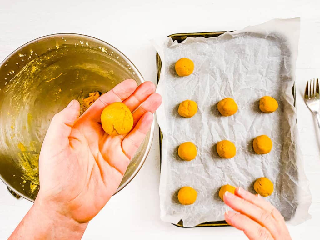 Peanut butter powder cookie dough balls rolled and placed on a baking sheet.