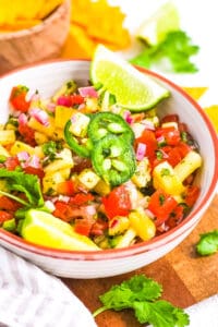 Pineapple pico de gallo served in a white bowl, garnished with jalapenos.