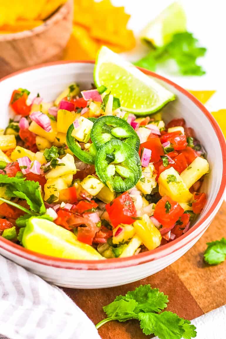 Pineapple pico de gallo served in a white bowl, garnished with jalapenos.
